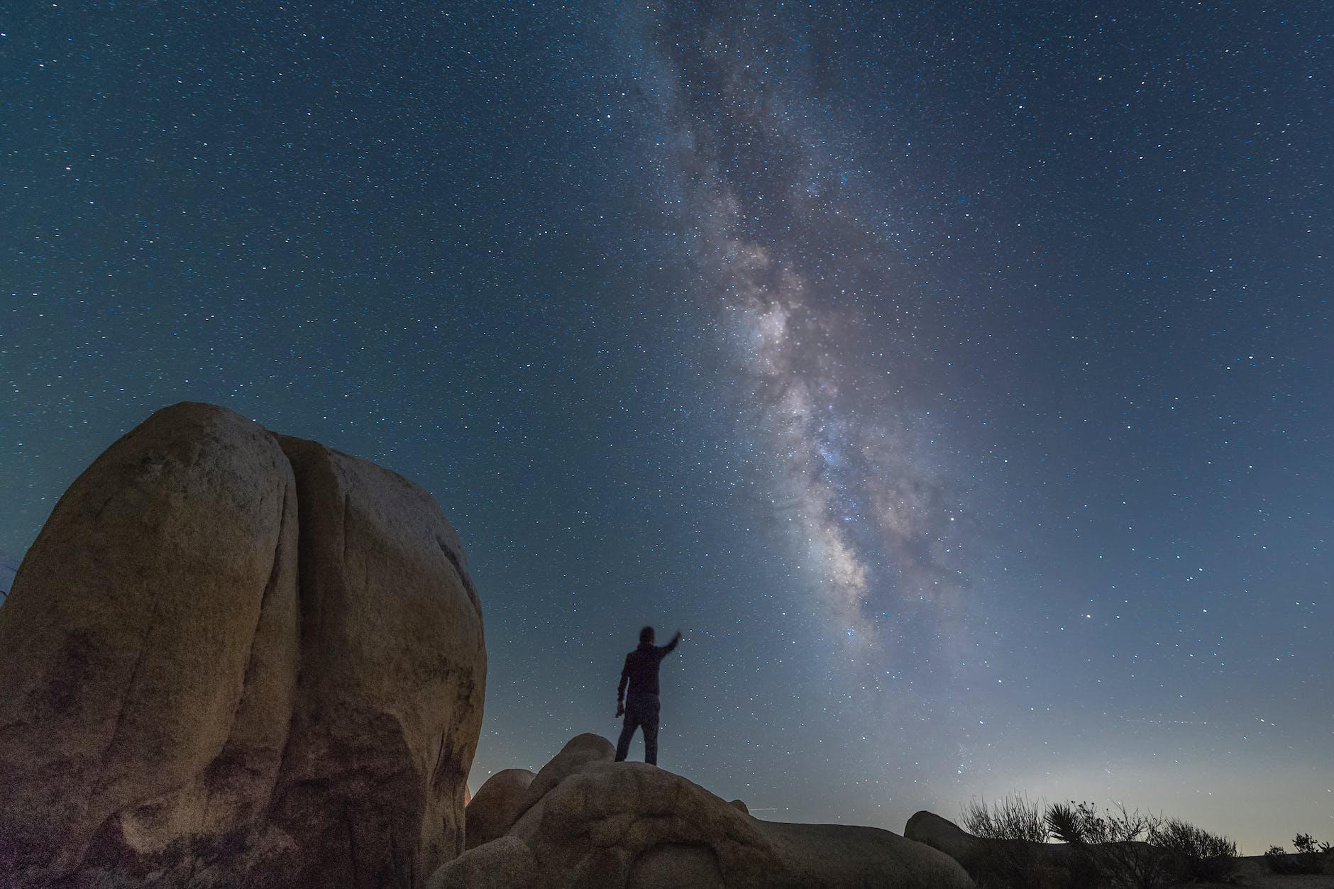 a person standing on a rock under a starry night sky